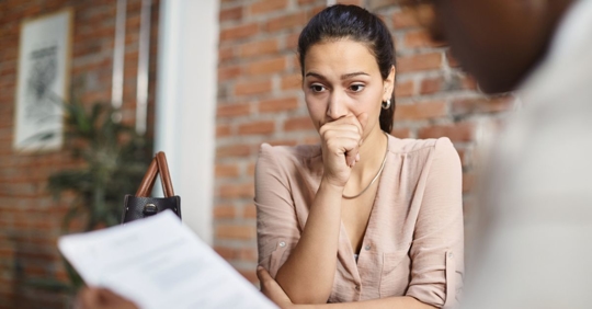 Woman Looking Nervous While Man Looks at Paper